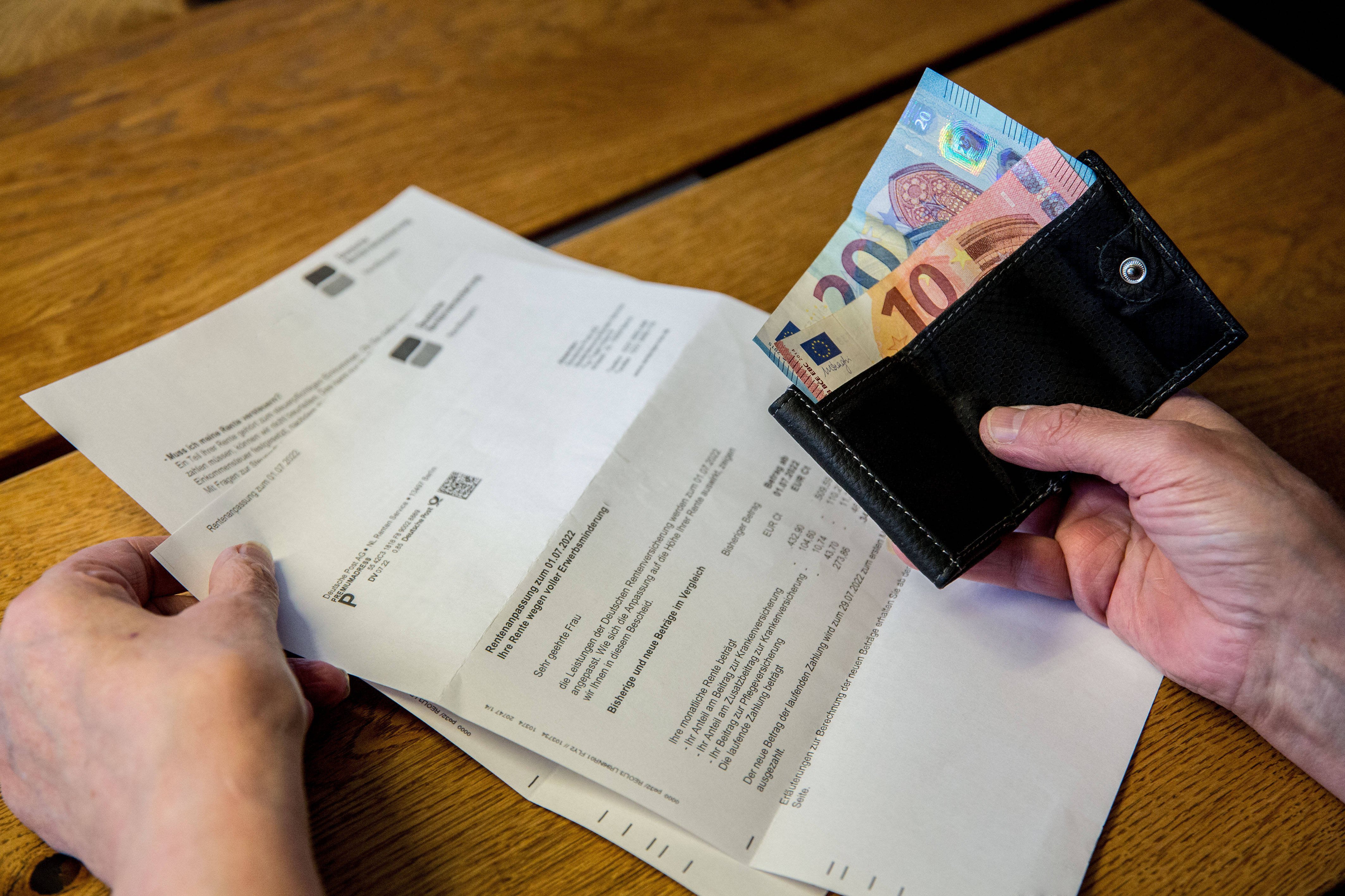 DRV informiert über Rentenerhöhung Eine ältere Person im Rentenalter sitzt an ihrem Tisch und hält eine Geldbörse, Portemonnaie, mit wenig Bargeld in den Händen. Die Geldscheine haben die Währung Euro und sind von unterschiedlichem Geldwert. Des Weiteren liegt ein Schreiben der Deutschen Rentenversicherung auf dem Tisch.