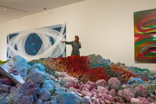 Stefanie Reimers steht in der Ausstellungshalle, schaut auf eine großformatige Installation und spricht ins Telefon.
