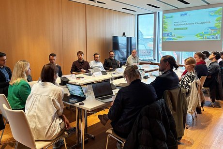 Teilnehmende des Kick-off-Workshops Klima im Mai 2026 in Berlin sitzen an einem Konferenztisch, auf einer Leinwand wird eine Pr&auml;sentation gezeigt.