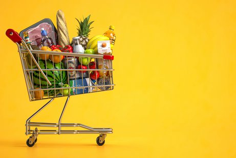 Lebensmittelpreise Ein kleiner Spielzeug-Einkaufswagen, gefüllt mit Miniaturen von Lebensmitteln