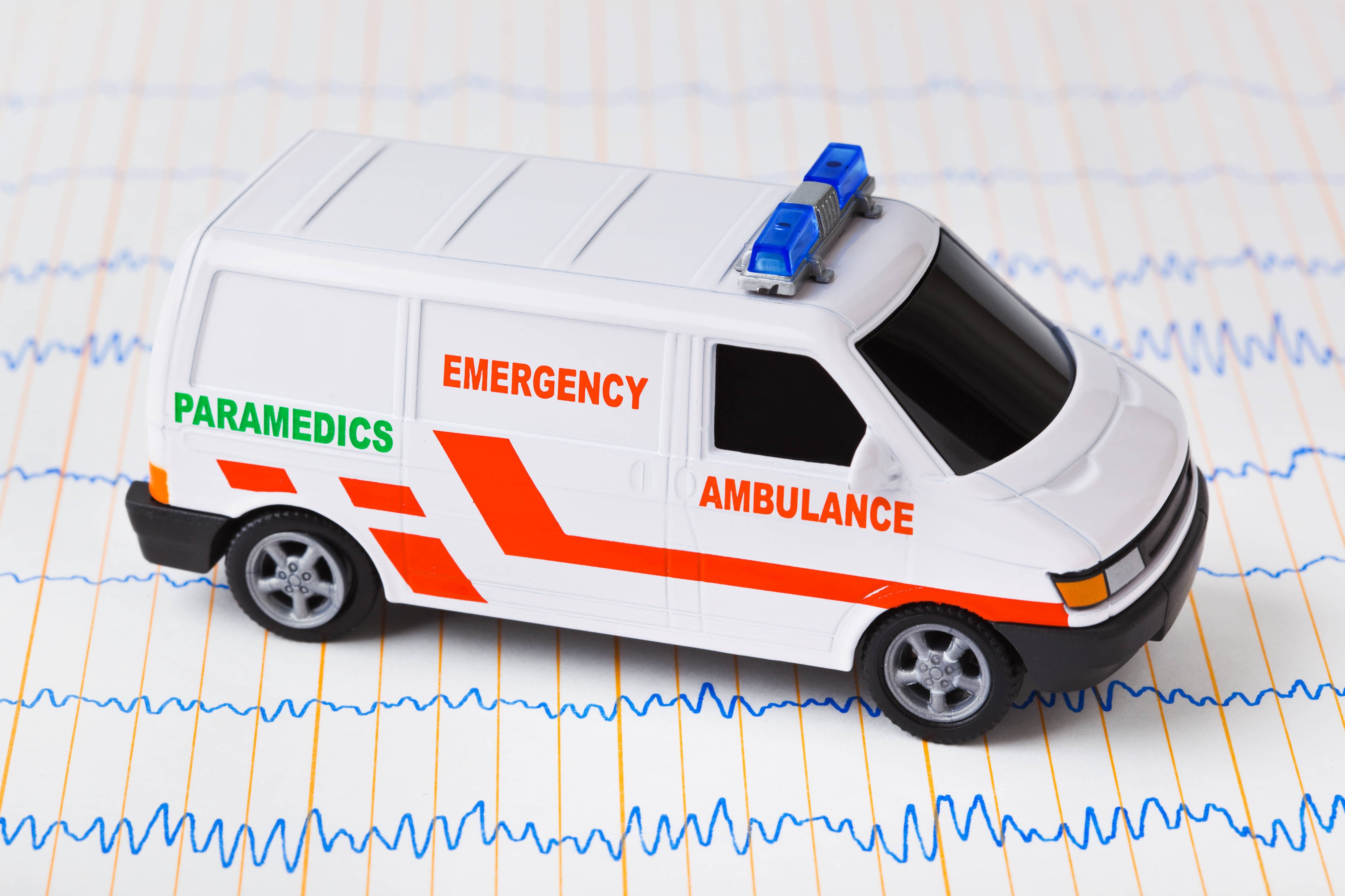 Ein Spielzeug-Krankenwagen steht auf einem Ausdruck eines medizinischen Diagramms, vielleicht eine Kardiogramms.