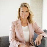 Das Foto zeigt Verena Bentele, sie sitzt in einem grauen Sessel und hat einen Arm auf der Lehne abgelegt