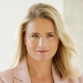 Das Foto zeigt Verena Bentele, sie sitzt in einem grauen Sessel und hat einen Arm auf der Lehne abgelegt