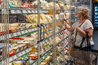 Einkaufen im Supermarkt Eine ältere Frau im Supermarkt, sie steht vor einem Regal voller Lebensmittel