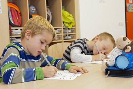 Kinder in einer inklusiven Schule Zwei Erstklässler sitzen in einer Schule am Tisch, schreiben etwas auf ein Arbeitsblatt.