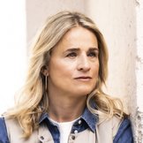 Verena Bentele steht mit vor der Brust verschr&auml;nkten Armen an eine Wand gelehnt, blickt ernst zur Seite.