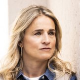 Verena Bentele steht mit vor der Brust verschr&auml;nkten Armen an eine Wand gelehnt, blickt ernst zur Seite.