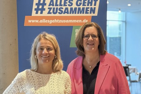 Parlamentarisches Frühstück VdK 2025 Das Foto zeigt Verena Bentele und Kerstin Griese, hinter ihnen steht ein Roll-up der VdK-Aktion "Alles geht zusammen".