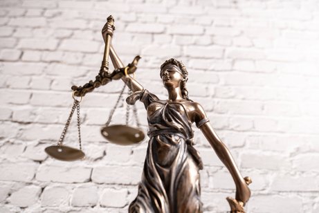 Justitia Justitia-Figur vor einer weißen Steinmauer