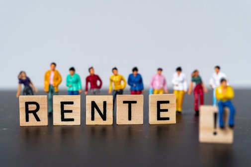 Buchstabenwürfel bilden das Wort Rente. Dahinter stehen kleine Figürchen, die sich teils auf die Würfel stützen, teils auch darauf sitzen.