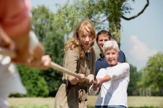 Ältere Frau, jüngere Fau und jüngerer Mann ziehen an einem Tau.