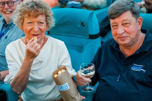 Eine Frau und ein Mann - beide ehrenamtlich Engagierte im VdK - sitzen im Kinosaal, essen Popcorn.