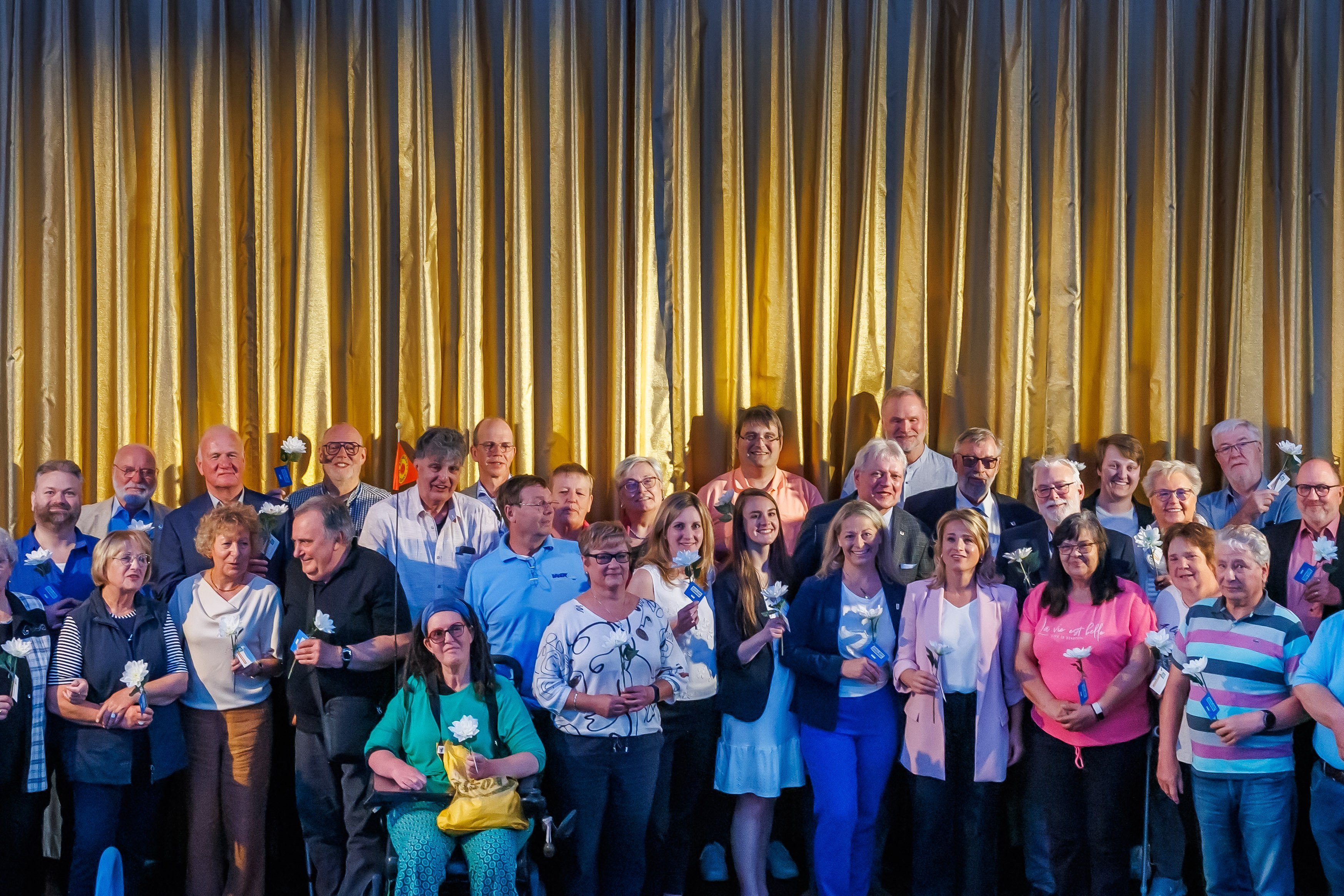 Gruppenfoto: Ehrenamtlich Engagierte auf der Bühne vor der Leinwand im Kino Delphi Lux in Berlin.