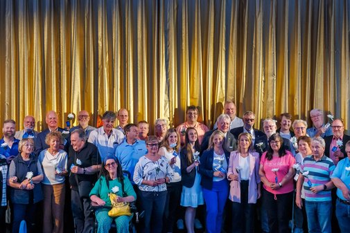 Gruppenfoto: Ehrenamtlich Engagierte auf der Bühne vor der Leinwand im Kino Delphi Lux in Berlin.