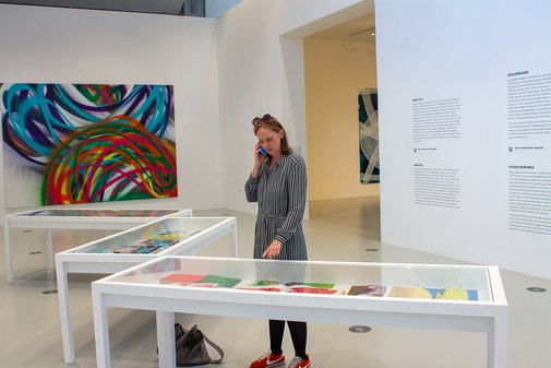 Stefanie Reimers betrachtet ein Ausstellungsstück, telefoniert dabei.