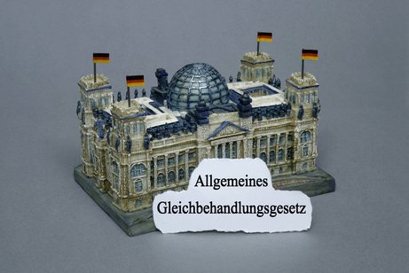 Bildmontage: Miniatur-Reichstag mit dem Schriftzug "Allgemeines Gleichbehandlungsgesetz"