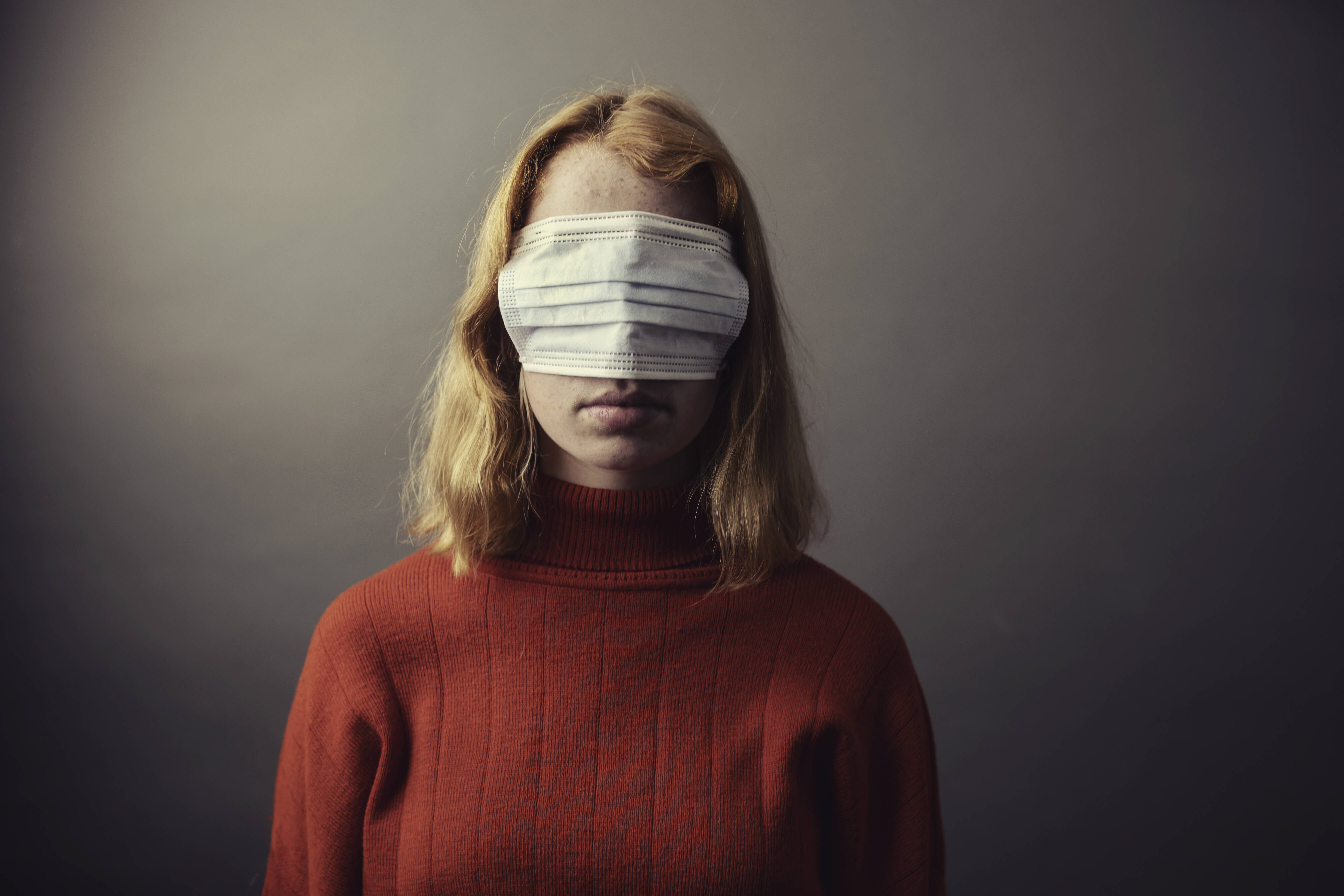 Gesundheitsängste Eine junge Frau hat eine Atemschutzmaske über die Augen gezogen, so dass sie nichts sehen kann.