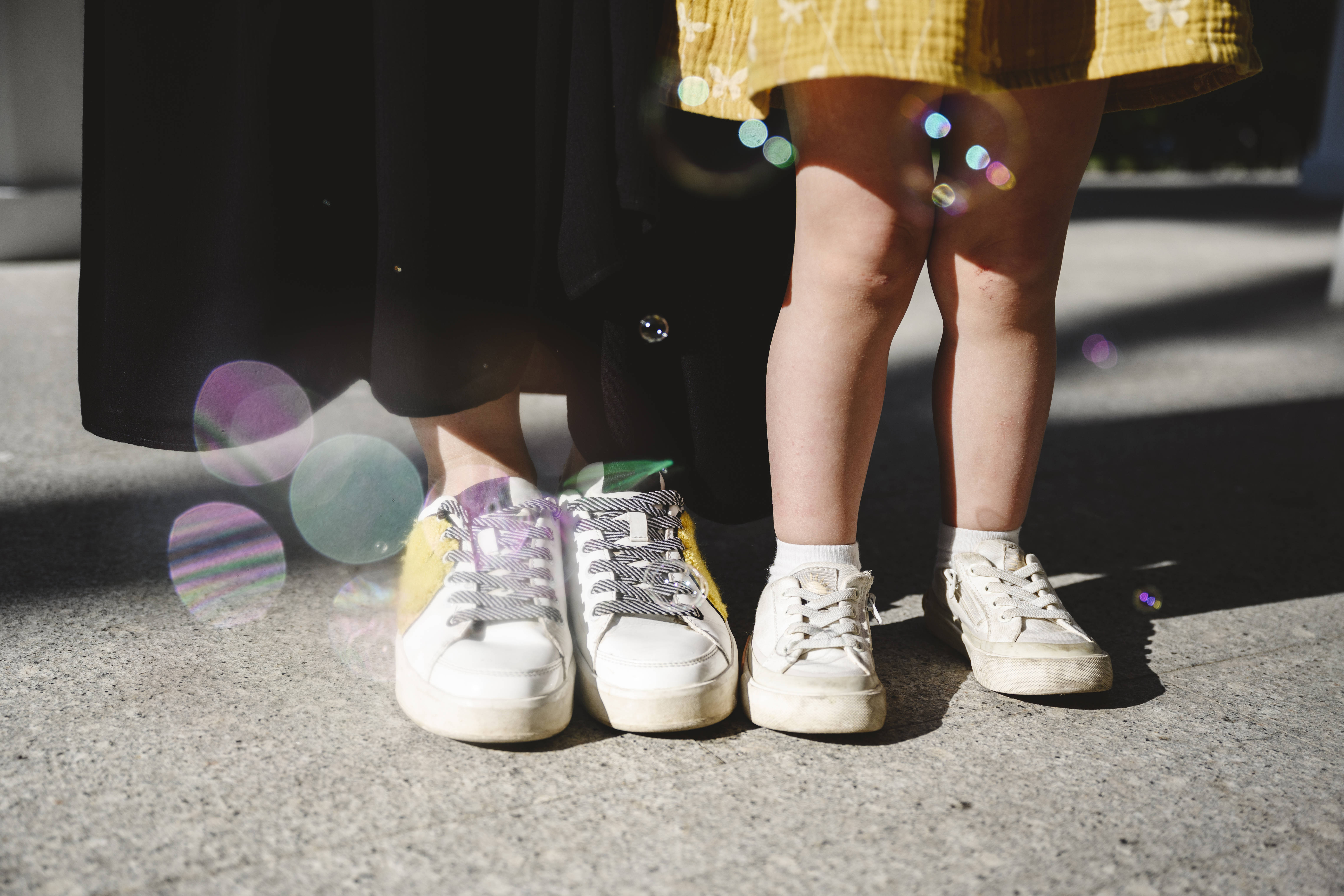 Mutter und Kind Frau und Kind stehen nebeneinander, beide tragen weiße Turnschuhe