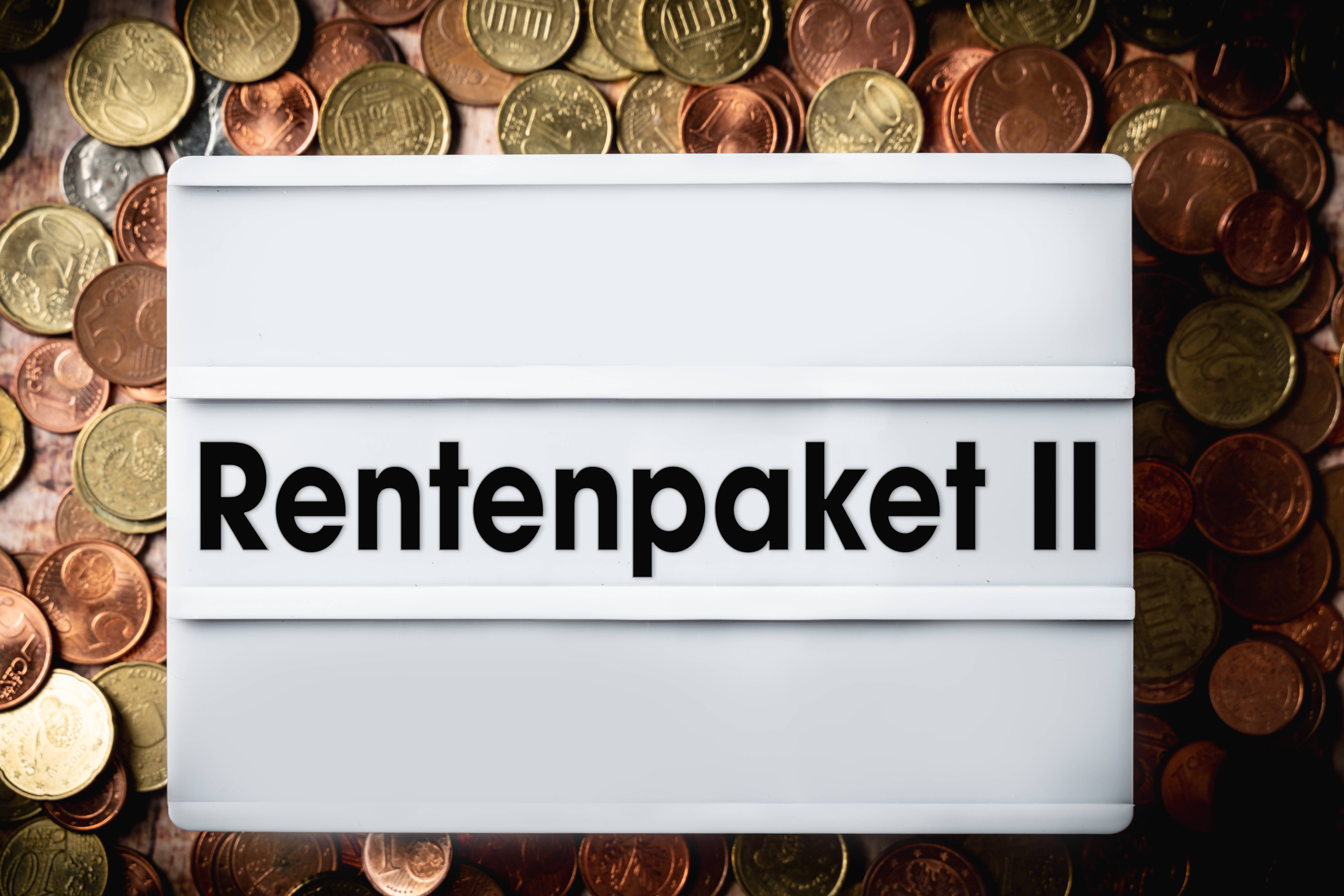 Rentenpaket II Die Fotomontage zeigt einen Mini-Leuchtkasten, in dem das Wort "Rentenpaket II" aus Buchstaben gebildet wurde. Der Leuchtkasten liegt auf einem Haufen Euro-Münzen.