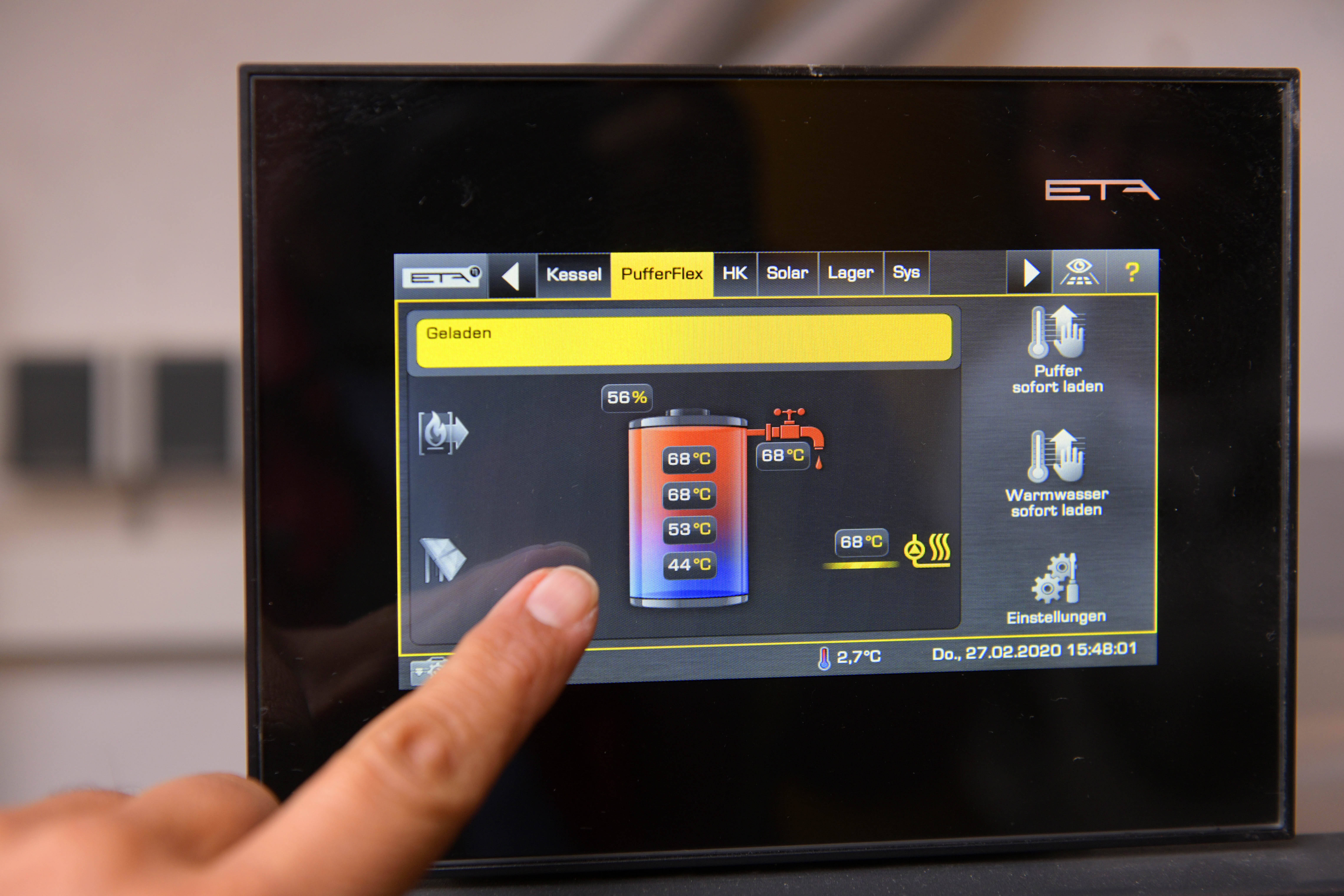Neu errichtete Holzpellet-Heizung im Keller eines Wohnhauses. Das Foto zeigt in Nahaufnahme das Display der Heizung mit dem Touchscreen-Bildschirm zur Bedienung der Anlage. 
