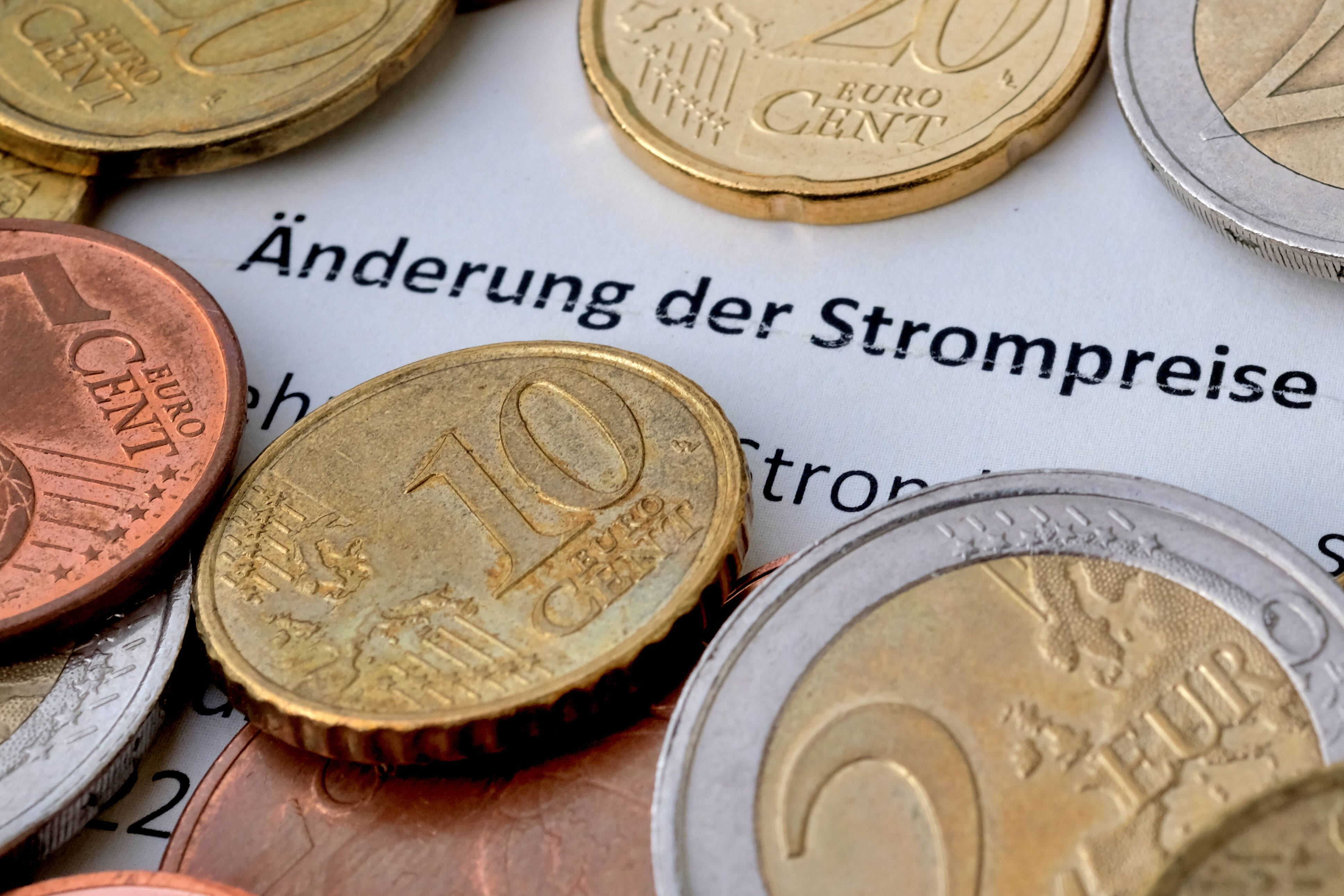 Ein Brief eines Energieversorgers, zu lesen ist "Änderung der Strompreise", darauf liegen Münzen