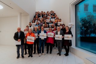 Mehrere Personen auf einer Treppe, die in die Kamera lächeln.