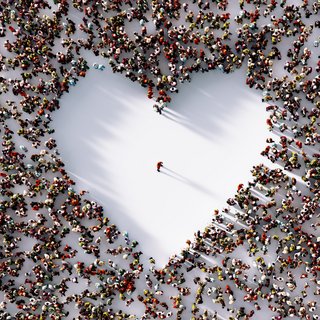 Alle für einen: Luftansicht einer einzelnen Person, steht in der Mitte einer Menschenmenge die ein herz formt