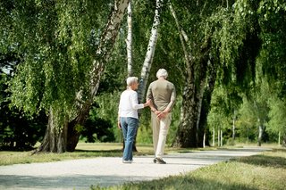 Das Foto zeigt ein älteres Ehepaar beim Spaziergang in einem Park.