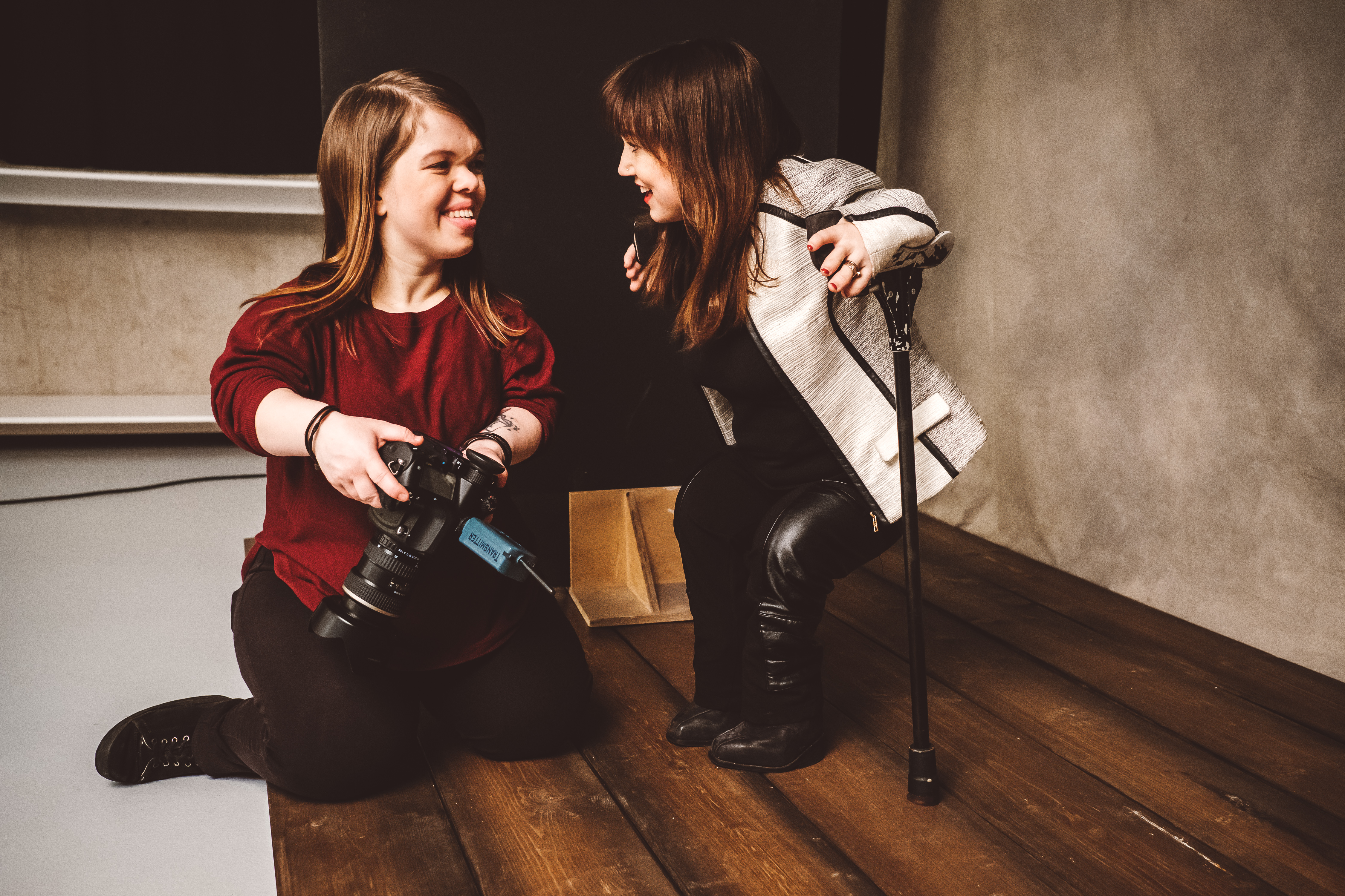 Fotografin Anna Spindelndreier (links) hält eine Fotokamera in der Hand und unterhält sich mit einem ihrer Models. Beide sind kleinwüchsig.