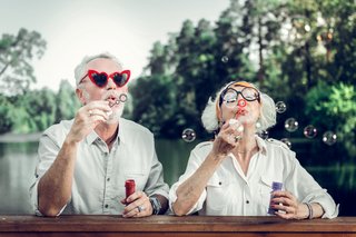 Eine Frau und ein Mann mit lustigen Brillen spielen mit Seifenblasen.