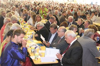 Menschenmenge an langen Tischen sitzend