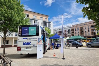 Man sieht den Infobus des VdK auf einem großen Platz. Es sind Info-Stände verschiedener Organisationen aufgebaut.