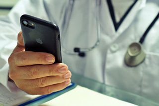 Ein Arzt hält ein Smartphone in der Hand.
