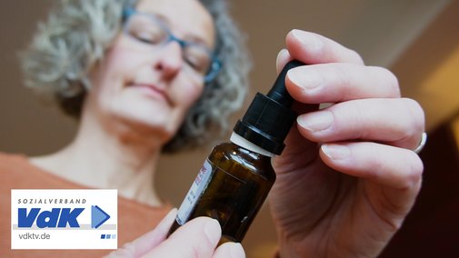 Eine Frau hat ein Fl&auml;schchen mit einer Pipette in der Hand und liest, was auf dem Etikett steht.