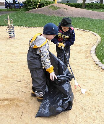 zwei Kinder sammeln Müll in einen großen Sack