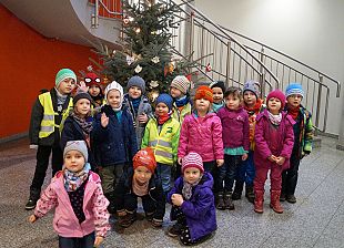 Kinder stehen vor einem schön geschmückten Tannenbaum