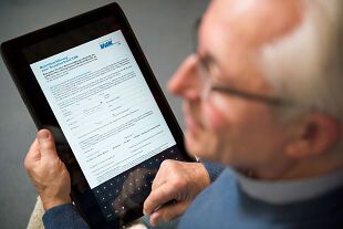 ein Mann füllt auf einem iPad eine Beitrittserklärung aus