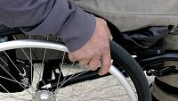 Bild zeigt eine Hand an einem Rollstuhlrat liegen