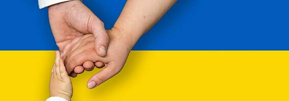 drei Hände berühren sich über der ukrainischen Flagge