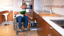 Rollstuhlfahrer in einer barrierefreien Küche