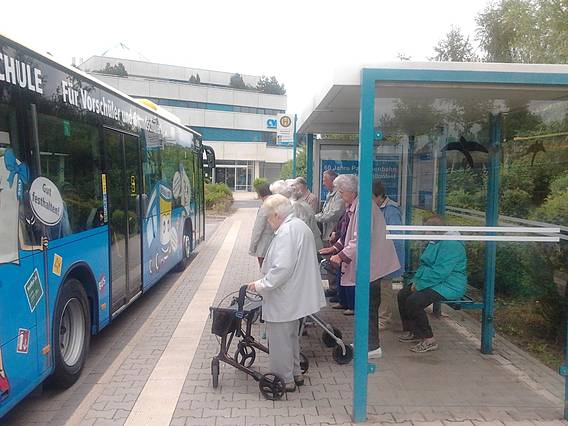 Senioren stehen am Einstieg an einem Bus