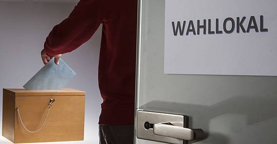 Symbolfoto: Jemand wirft in einem Wahllokal den Stimmzettel in einen Kasten.
