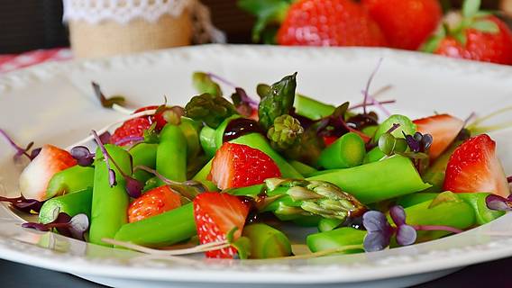 Symbolfoto: Ein Teller mit einem bunt angerichteten Salat aus Spargel, Erdbeeren und frischen Kräutern