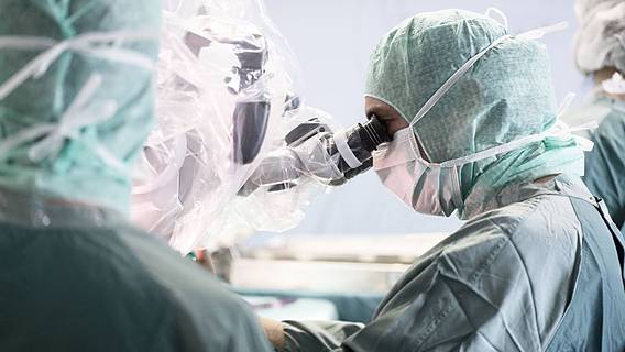 Symbolfoto: Ein Chirurg blickt bei einer Operation durch ein OP-Mikroskop.