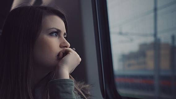 Ein Frau schaut melancholisch aus dem Fenster eines Zuges.
