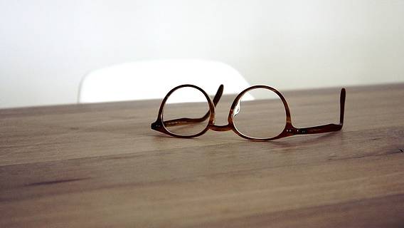 Das Bild zeigt eine Brille, die auf einem Tisch liegt.