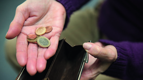 Das Bild zeigt die Hand einer älteren Person, die Münzen hält.