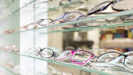 Das Bild zeigt ein Optikergeschäft mit vielen Brillengestellen auf Glasregalen.