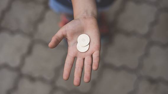 Das Bild zeigt eine Hand mit einer Münze darin