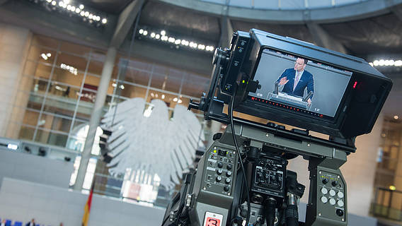 Das Bild zeigt den Bundestag, eine Kamera ist auf Jens Spahn gerichtet